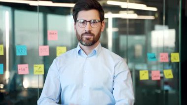 İş yerinde kollarını kavuşturmuş duran gözlüklü mutlu bir işadamının portresi. Kameraya bakarak gülümseyen başarılı bir menajer. Yakışıklı patronun kafasından.