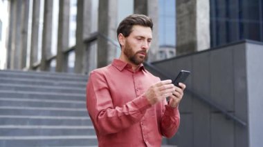 Hayal kırıklığına uğramış sakallı işadamı, bir iş yeri binasının yanında caddede dururken cep telefonundan kötü haberler okuyor. Hüzünlü adam nahoş bir haber yüzünden üzgün, mesajla bunalıma girmiş.