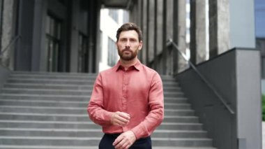 Şehir merdivenlerinde duran, kırmızı gömlek ve kollarını kavuşturmuş kendinden emin iş adamının portresi. Profesyonellik, kararlılık ve liderlik yayıyor. İş, girişimci ya da şirket kavramı