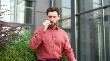 Stresli sakallı iş adamı ofis dışında mola verirken gözlüğünü çıkarıyor. Yorgun erkek işçi masajı, burun köprüsü. Yoğun kentsel çalışma ortamında insan yorgunluk belirtileri gösterir