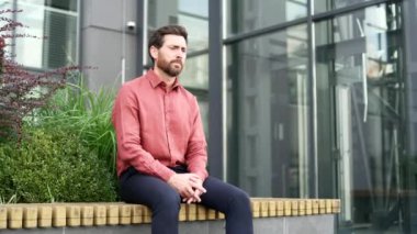 İş adamı ofis binasının dışında oturan stresli ve bunalmış görünen zihinsel acıdan muzdarip. Erkek zihinsel mücadele gösterir, hayal kırıklığı içinde başını tutar.