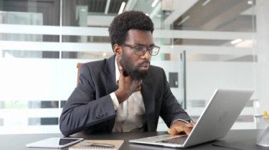 Bir iş yerinde dizüstü bilgisayarla çalışırken boğazı ağrıyan hasta Afrikalı Amerikalı iş adamı. Siyah adam nezle, virüs ya da grip olmuş. Üzgün erkek masaj yarası var.