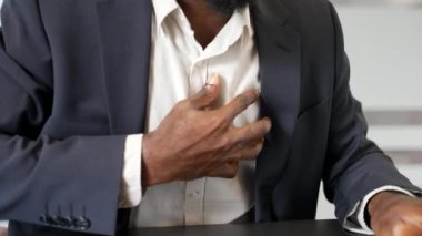 Kapatın. Masaj sandığı tutan Afrikalı Amerikalı erkek elleri. Resmi takım elbiseli bir işadamı iş yerinde otururken kalp krizi geçirdi. Hasta zenci işçinin tıbbi yardıma ihtiyacı var.