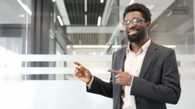 Mutlu Afro-Amerikan iş adamı iş yerinde mesaj yazmak için boş alanı işaret ediyor. Siyah adam kameraya bakıyor. Reklam şablonu. Mal tanıtımı için boşluk kopyala