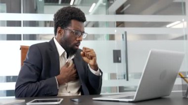 İş yerinde otururken öksüren Afro-Amerikalı işadamı. Soğuk algınlığı ya da resmi takım elbiseli grip çalışanı elini göğsüne dayayıp kendini kötü hissediyor. Siyah adamda bronşit var.