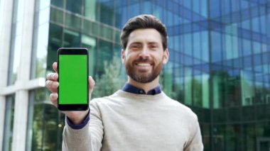 Cam ofis binasının yakınında kameraya bakarak duran kendine güvenen, yeşil ekranlı bir erkek girişimci. Reklam için renk anahtarı dikey şablon düzeni