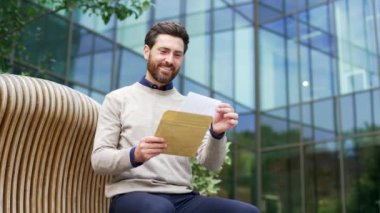 Kentsel ortamdaki mutlu iş adamı önemli bir haber aldıktan sonra heyecanını dile getiriyor. Şehirde elinde neşeli bir ifade olan bir erkek. Başarı kavramı, başarı ve olumlu haber