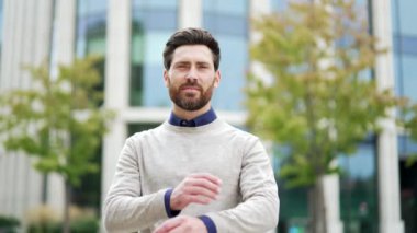 İş yeri binasının yanında kolları bağlı duran kendine güvenen profesyonel bir erkeğin portresi. Şehir ortamında gülümseyen mutlu iş adamı pozitif tavır sergiliyor