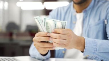 Kapatın. Erkek eller 100 dolarlık banknotları sayar. İş yerindeki banknotları sayan Afrikalı Amerikalı iş adamı. Siyahi adamın elinde nakit para var. Finansal başarı kavramı.