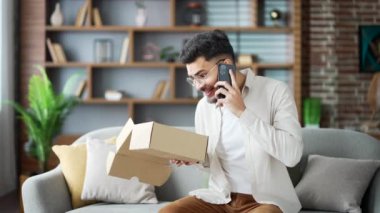 Kanepede oturan hayal kırıklığına uğramış genç bir adam online alışveriş konusunda hayal kırıklığını dile getiriyor. Öndeki kutuyu açmak teslimat sorunu demektir. Mutsuz erkek yanlış ürünle paket alıyor.