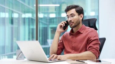 Modern ofiste işyerinde otururken kendine güveni tam bir yönetici telefonda konuşuyor. Gözlüklü yakışıklı iş adamı müşterisiyle iletişim kurar ya da iş ortağıyla sohbet eder.