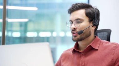 Müşteri desteğinde çalışan bir şirket operatörü bilgisayar kullanarak bir video görüşmesinde konuşuyor. Kablosuz kulaklıklı merkez ajanını ara. Ofisteki şikayetleri için müşterilere yardım et. Online danışmanlık. Kapat.