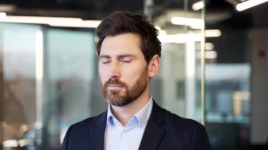 İş yerindeki resmi takım elbiseli mutlu bir işadamının portresi. Kameraya bakarak poz veren başarılı, güler yüzlü adam. Yakışıklı patronun kafasından. Kapat.
