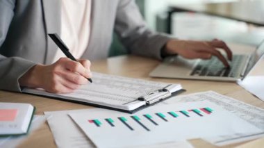 Bir kadın eli dolgu kalemle dolduruyor. Muhasebeci, dizüstü bilgisayarında daktilo kullanarak finansal hesaplamalar yapıyor. Takım elbiseli iş kadını boş vergi formu dolduruyor.