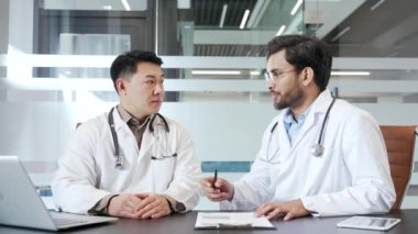 Ofiste iş birliği yapan iki doktor, bir toplantı sırasında tıbbi stratejiler ve hasta bakımı planlarını tartışıyorlar. Tıp doktorları hastaların tedavisi hakkında danışmanlık yapar, iletişim kurar, tavsiyelerde bulunurlar