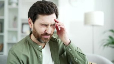 Göz yorgunluğu ve baş ağrısı çeken yakışıklı bir adam evdeki oturma odasında kanepede oturuyor. Aşırı yorgun, sakallı erkek gözlüğünü çıkarır ve eliyle burnuna masaj köprüsü yapar. Kapat.