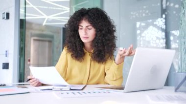 Finansal sonuçlardan memnun olmayan hayal kırıklığına uğramış kadın finansör iş yerindeki masada oturan bilgisayardaki belgeleri kontrol ediyor. Kafası karışmış iş kadını kötü göstergelerden memnun değil