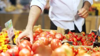 Süpermarkette sebze seçen erkek ellerin yakın çekimi. Çiftlik pazarından bir adam domates topluyor.