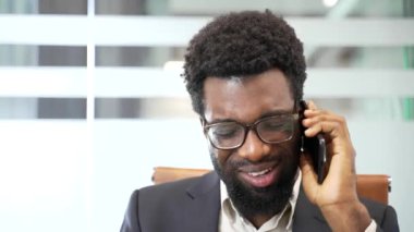 Kızgın, hoşnutsuz Afro-Amerikan iş adamı iş yerindeki iş yerinde telefonla konuşuyor. Heyecanlı siyah adam, çözülmesi gereken sorunlar hakkında duygusal olarak konuşur. Kapat.