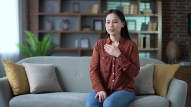 Asyalı kadın evdeki oturma odasında kanepede otururken kalp krizi geçiriyor. Hasta kadın göğsündeki gerilimden muzdarip ve elleriyle hassas noktayı tutuyor. Acil tıbbi yardıma ihtiyacı var.