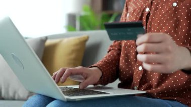 Evdeki koltukta kredi kartıyla çevrimiçi işlem yapmak için dizüstü bilgisayarda yazan Asyalı kadın ellerini kapat. Kadın alışverişçi dijital ödeme yapıyor, İnternet, e-ticaret, e-alışveriş için para harcıyor