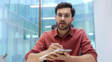 Webcam görüntüsü. İş adamı internetten video konferans notlarını izliyor. Dizüstü bilgisayarın ekranına bakıyor. Ofiste oturuyor. İşçi uzak iş toplantısı, eğitim