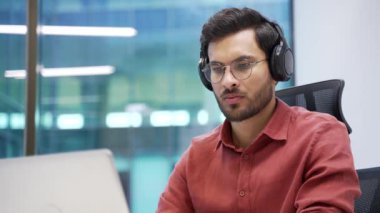 Kablosuz kulaklıklar üzerine odaklanmış bilişim uzmanı iş yerindeki bir laptopta çalışıyor. Yakışıklı kodlayıcı kod yazar. Geliştirici programlıyor, bilgisayardaki bir projeyle meşgul. Kapat.