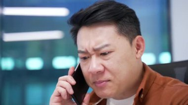 Kızgın Asyalı işadamı iş yerinde otururken cep telefonuyla konuşuyor. Heyecanlı hoşnutsuz patron sorunlar hakkında astlarıyla tartışıyor, öfkesini dile getiriyor. Kapat.