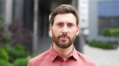 Ofis binasının önünde duran kırmızı gömlekli, güler yüzlü bir iş adamının portresi. Dost canlısı sakallı adam kameraya bakıyor. Sahibinin, menajerinin ya da işçisinin vesikalığı. Kapat.
