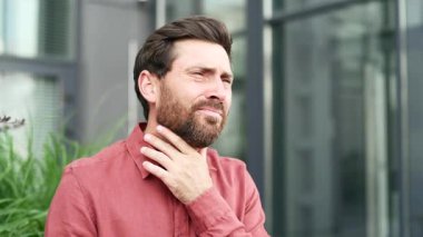 İş yerinin yakınındaki bir bankta otururken boğazı ağrıyan kırmızı gömlekli hasta işadamı. Bir adam nezle, virüs ya da grip olabilir. Hassas bir noktaya masaj yapan üzgün bir erkek. Kapat.