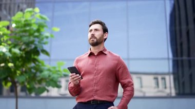 İş adamı şehir merkezinin dışında yürüyor, elinde akıllı telefon, gülümsüyor. Kırmızı tişörtlü kendine güvenen adam şehir ortamının tadını çıkarıyor. Ofis çalışanı şehir caddesinde profesyonel iletişimle meşgul.