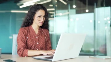 İş yerindeki iş yerinde oturan dizüstü bilgisayarında yazılımla veya servisle ilgili sorunları olan endişeli bir iş kadını. Hayal kırıklığına uğramış kadın çalışan kötü internet bağlantısından şikayetçi