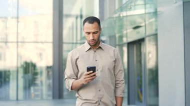 Genç bir adam ofis binasının önünde yürürken telefonuna bakıyor. Yakışıklı bir işadamı cep telefonu kullanıyor. Bir erkek akıllı telefon mesajları işiyle uğraşırken mesajlaşıyor. 