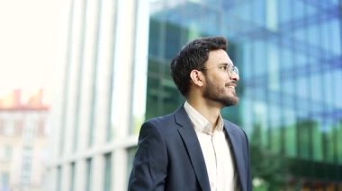 Takım elbiseli kendine güvenen bir işadamı bir ofis binasının yakınındaki caddede yürüyor. Modern şehrin merkez ticaret bölgesinde gözlüklü, sakallı bir girişimci yürüyor. Yakışıklı menajer işe gidiyor. Kapat.