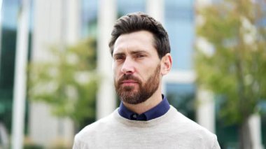 İş yerinin yakınındaki caddede kameraya bakarak duran kendine güvenen ciddi profesyonel erkek portresi. Olgun erkek profesyonel dışarıda poz veriyor, liderlik ve başarı sergiliyor.