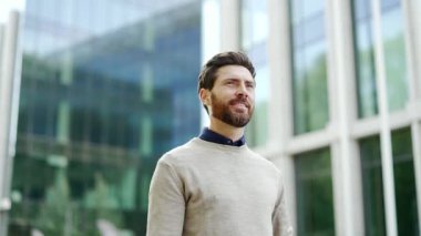 Profesyonel iş adamı ofis binasının yakınındaki şehir manzarasında rahatça dolaşır. Olgun, sakallı bir adam modern kentsel çevreden hoşlanır, pozitiflik ve başarı yayar. Şirket ortamında iş hayatı
