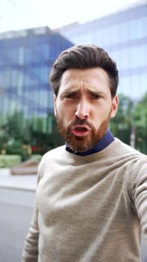 Web kamerası görüntüsü dikey. Öfkeli hoşnutsuz iş adamı telefonda konuşurken iş yerinin yakınındaki caddede duran kameraya bakıyor. Sorunlar hakkında heyecanlı yönetici konuşmaları
