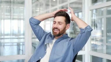 Mutlu iş adamı iş yerindeki bir sandalyede otururken ellerini başının arkasına koyuyor. Gülümseyen yakışıklı erkek teneffüste gözleri kapalı rahatlar. Kapat.