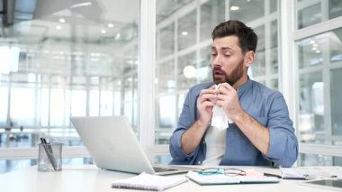 Alerjik işadamı, modern bir iş bürosunun çalışma masasında otururken hapşırır ve burnunu mendille siler. Sezonluk alerjisi olan hasta, yakışıklı sakallı bir adam.