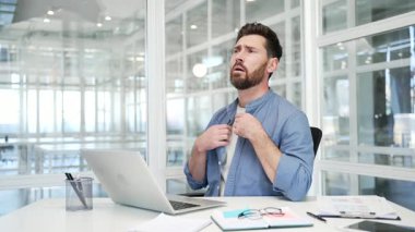 İş adamı, modern bir iş ofisinde çalışma masasında otururken seksidir. Adam ellerini vantilatör gibi sallıyor, işine konsantre olamıyor, çünkü odadaki klima bozuk.