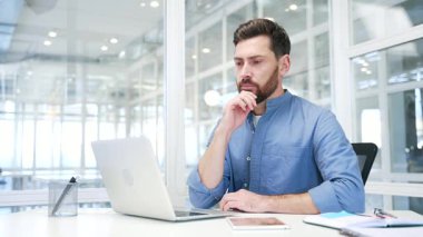 İş yerinde dizüstü bilgisayarla çalışan düşünceli bir iş adamı. Müdür, iş yerinde oturarak problem çözmeyi düşünüyor. Girişimci ya bir işle meşguldür ya da bilgisayardaki bir projeyle meşguldür