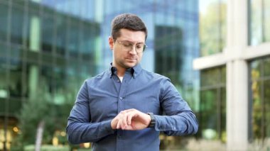 Kendine güveni tam bir işadamı, modern ofis binasının yanındaki caddede dururken ukalalık yapıyor. Gözlüklü bir iş adamı akıllı saate bakar ve bir uygulama kullanır. Yakışıklı erkek işçi bildirimleri kontrol eder