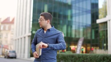 İş adamı kol saatine bakar ve şehir caddesinde koşar. Erkek işçi işe geç kalır. Girişimci bir toplantıya yetişmek için acele ediyor. Adamın iş görüşmesi için acelesi var. Ön görünüm