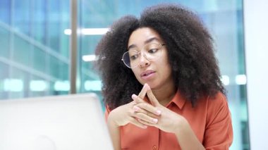 Kendine güvenen Afro-Amerikalı iş kadını ofiste dizüstü bilgisayarla görüntülü konuşma yapıyor. Kadın yönetici online bir konferansta iletişim kurar ya da iş ortağıyla uzaktan sohbet eder. Kapat.