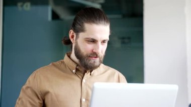 Kendine güvenen bir iş adamı, modern bir ofiste iş yerinde oturan bir dizüstü bilgisayarla video görüşmesinde konuşuyor. Girişimcinin iş toplantısı var. Müdür çevrimiçi konferansta uzaktan konuşuyor. Kapat.