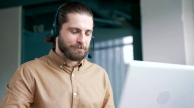 Müşteri destek servisinde çalışan bir şirket operatörü. Yardım hattında çalışıyor. İş yerinde dizüstü bilgisayarla konuşuyor. Çağrı merkezi temsilcisi, müşteriye soruları cevaplayarak tavsiyede bulunur. Kapat.