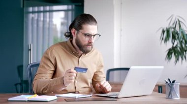 Şok olmuş işadamı iş yerindeki bilgisayarından kredi kartını kontrol ediyor. Hüsrana uğramış erkek, aldatma kurbanı oldu, dolandırıcılıkla yüzleşti, hesabından para çalındı.