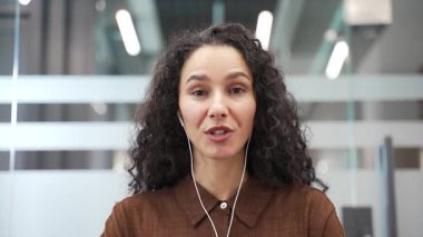 Webcam görüntüsü. Kulaklıklı bir iş kadını video konferansında ofisteki kameraya bakıyor. Kadın yönetici online toplantıda iletişim kurar ya da iş ortağıyla uzaktan sohbet eder. Kapat.