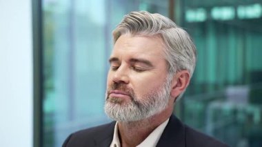 Olgun iş adamı iş yerinde gözleri kapalı dinleniyor. Resmi takım elbiseli sakin, mutlu bir işçi işte dinleniyor derin bir nefes alıyor, iç huzuru hissediyor, stresi atıyor. Kapat.