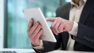 Modern iş ofisindeki çalışma masasında dijital tableti tutan erkeklerin ellerini kapatın. Resmi takım elbiseli işadamları uygulama, daktilo, sohbet, bankacılık veya internette gezinme üzerinde çalışıyor